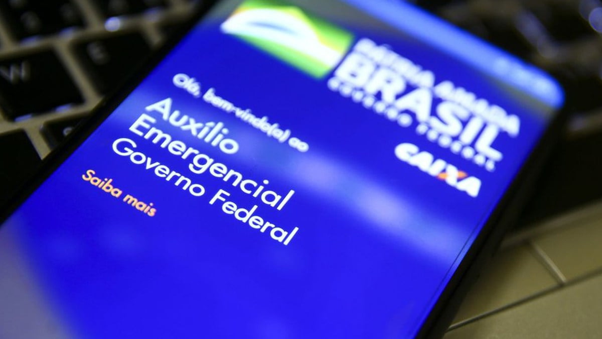 celular em cima de um teclado que mostra a tela inicial do app do auxílio brasil