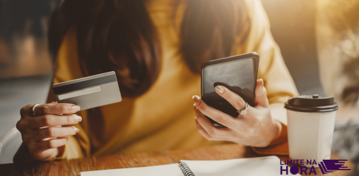 Mulher com celular e cartão na mão simulando um emprestimo com cartão de crédito