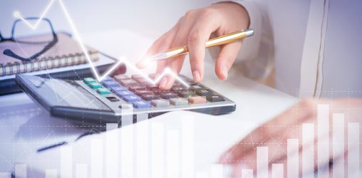 uma mesa, mãos de uma pessoa fazendo contas em uma calculadora e olhando em um caderno. sobre a foto, imagem de um gráfico brilhante