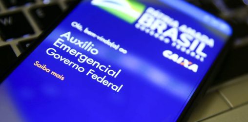 celular em cima de um teclado que mostra a tela inicial do app do auxílio brasil