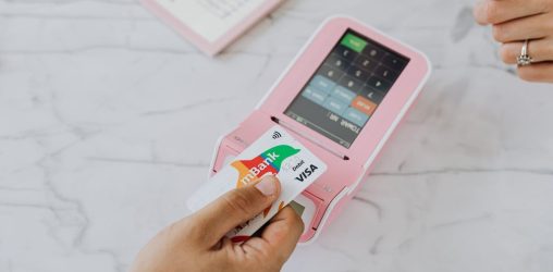 pessoa passando cartão na maquininha, representando as bandeiras de cartão de crédito