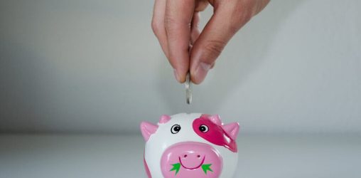 Pessoa colocando moeda em cofre de porquinho para economizar na pandemia