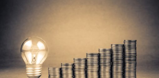 moedas empilhadas ao lado de lâmpada, representando o empréstimo de 5 mil