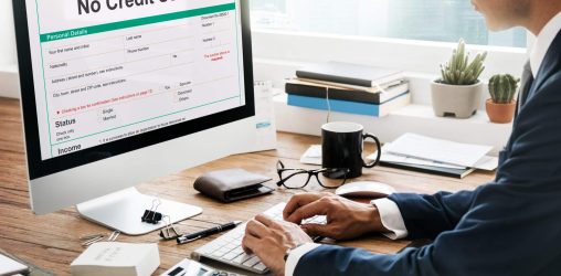 foto de homem vestido de terno sentado na frente de um computador lendo a mensagem "sem credito" em inglês