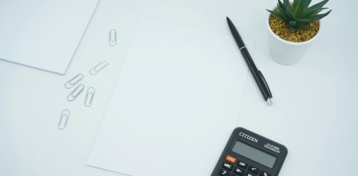 mesa com papel, calculadora e caneta, representando o que é anuidade do cartão
