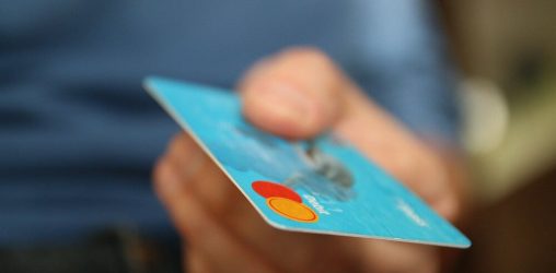 mão segurando cartão de crédito para a tela