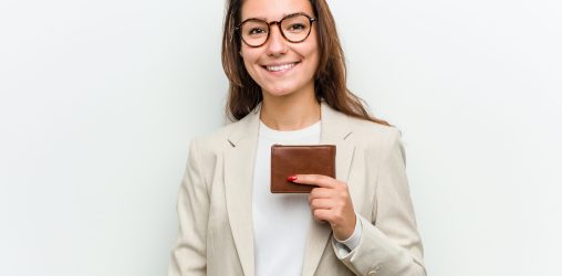 Young european business woman holding a wallet happy, smiling and cheerful.